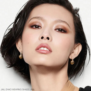 תמונת ביוטי של הדוגמנית Jiali Zhao עם איפור מלא, כולל בסיס אחיד, סומק עדין, שפתיים בגוון טבעי ועיניים מודגשות בצלליות חומות וברונזה. בתחתית התמונה מצוין כי היא לובשת את הגוון Lima.