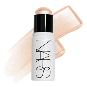 סטיק ההארה Light Reflecting Luminizing Stick של NARS בגוון Eros, מוצג פתוח לצד מריחה של הפורמולה על רקע בהיר. התמונה מדגישה את הגוון הפנינתי ואת הגימור הזוהר והקורן, המעניק הארה טבעית וברק עדין לעור.