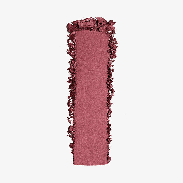 מריחה של הסומק הפנינתי Light Reflecting Luminizing Blush של NARS בגוון ורוד-שזיפי על רקע בהיר. התמונה מדגישה את המרקם המשיי, הגימור הפנינתי והזוהר, ואת הפיגמנט העדין והקורן של הסומק.