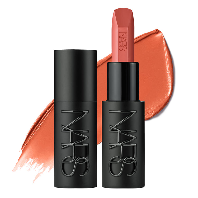 שפתון NARS בגוון אפרסק במרקם סאטן, מוצג פתוח לצד המכסה השחור ועל רקע מריחת צבע תואמת. אריזת השפתון השחורה עם לוגו NARS מוטבע, והגוון מעניק מראה טבעי וזוהר לשפתיים.